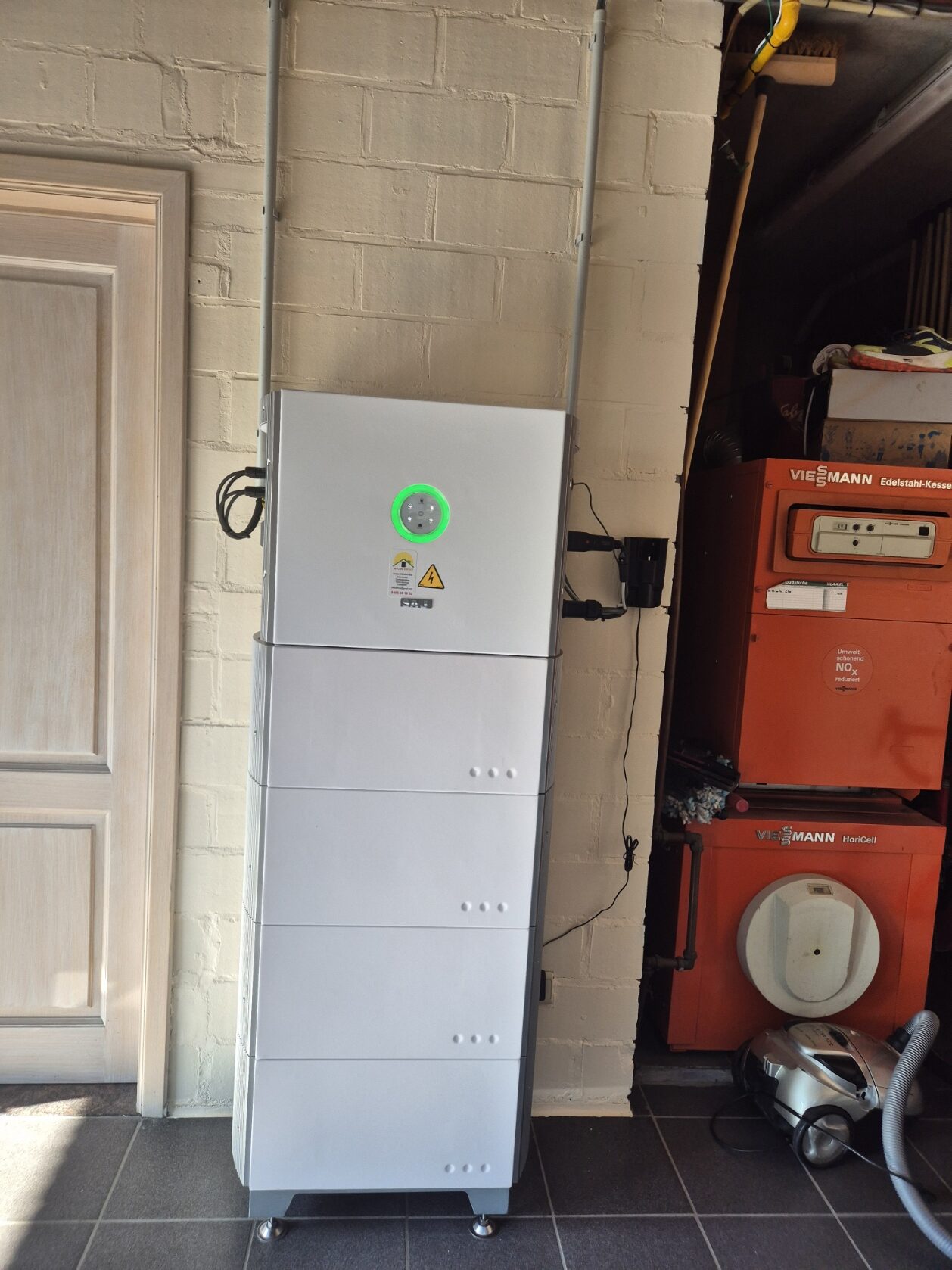 Staande thuisbatterij naast de binnendeur van een garage